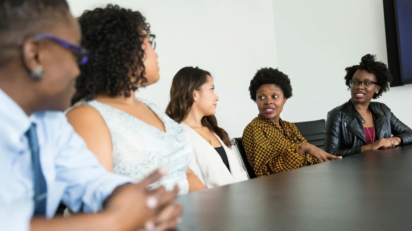 Five colleagues discuss ideas around a conference table.