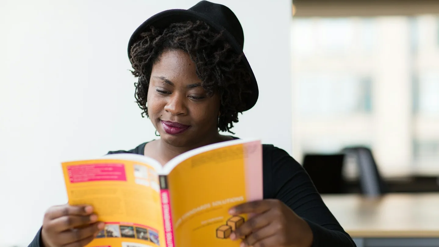A woman reads a book in a shared workspace.